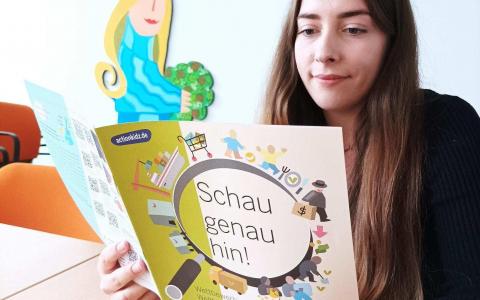 Ein Mädchen liest ein Heft mit der Aufschrift "Schau genau hin!". Quelle und Rechte: kindernothilfe.de