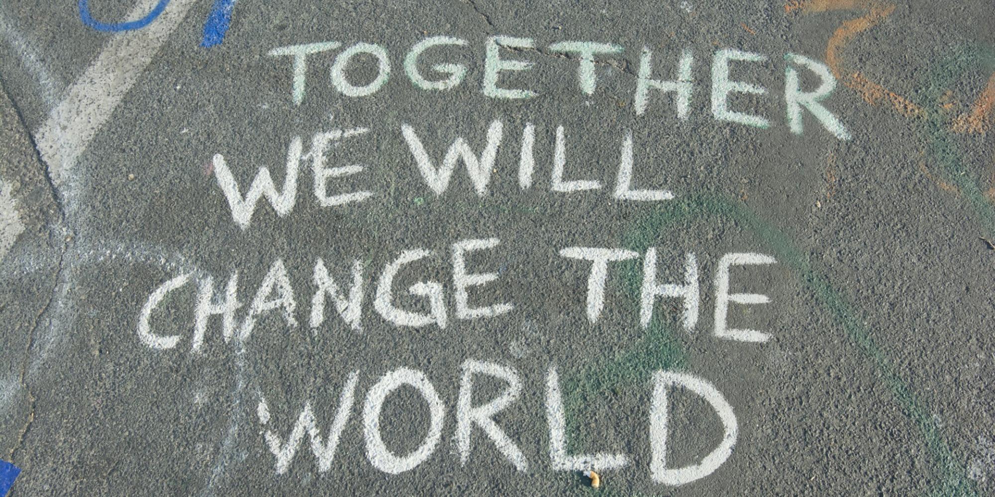 Kreidegraffito auf Asphalt mit den Worten "Together we will change the world"